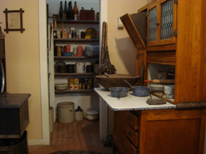 1900s kitchen with Hoosier cabinet and a pantry in the background.
