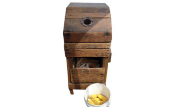 1870s wooden corn sheller with a bucket of corn.