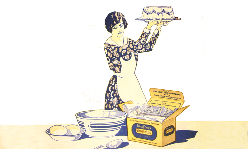 woman holding up a cake on a tray that she just baked with shortning.