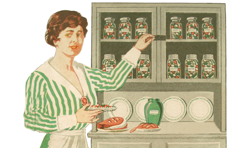 woman with apron pointing to hoosier cabinet to jars of pickled foods.