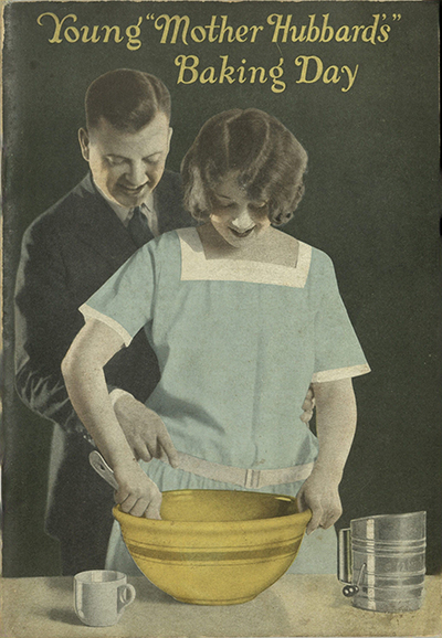 Man reaching behind cook, helping her stir.